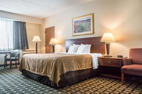 a hotel room with a bed and a chair at Quality Inn & Suites Palm Island Indoor Waterpark in Batavia