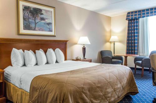 a hotel room with a large bed and chairs at Clarion Hotel and Conference Center in Ronkonkoma