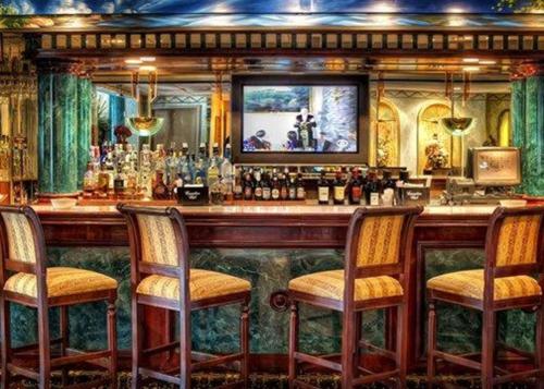 a bar with three chairs and a counter with bottles at Garden Place Hotel in Buffalo