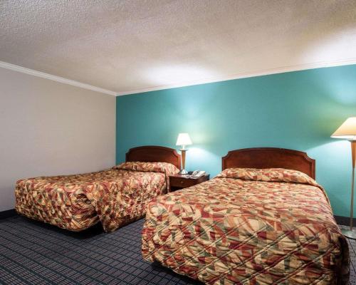 two beds in a hotel room with blue walls at Rodeway Inn Syracuse Carrier Circle in East Syracuse