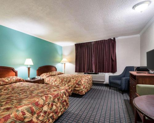 a hotel room with two beds and a television at Rodeway Inn Syracuse in East Syracuse