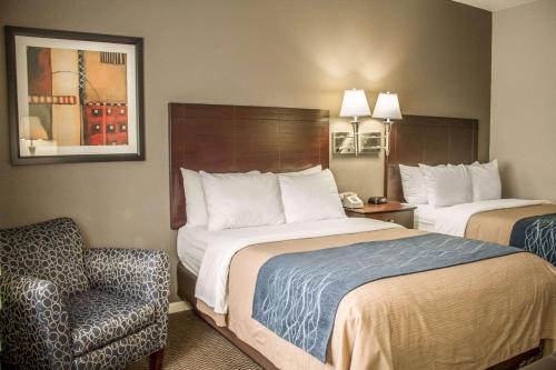 a hotel room with two beds and a chair at Comfort Inn Sandusky in Sandusky