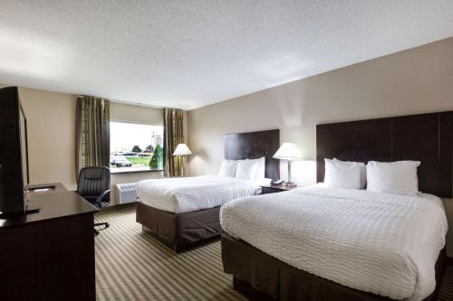 a hotel room with two beds and a flat screen tv at Clarion Hotel Beachwood-Cleveland in Beachwood