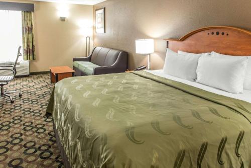 a hotel room with a large bed and a chair at Quality Inn & Suites Columbus West - Hilliard in Columbus