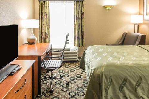 a hotel room with a bed and a desk and a television at Quality Inn & Suites Columbus West - Hilliard in Columbus