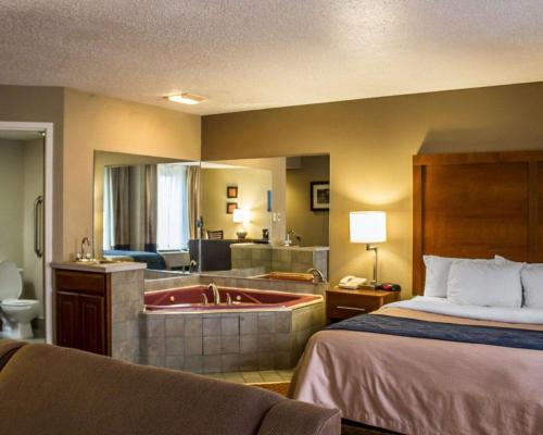 a hotel room with a bed and a bathroom with a tub at Quality Inn in Akron