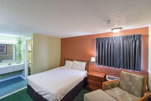 a hotel room with a bed and a chair at Rodeway Inn Wauseon in Wauseon
