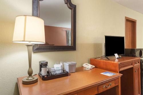 a desk in a hotel room with a lamp and a mirror at Rodeway Inn Wauseon in Wauseon