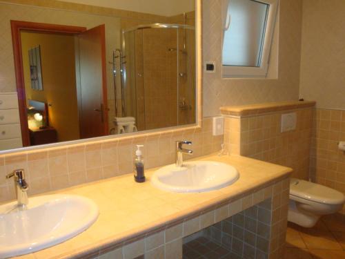 a bathroom with two sinks and a toilet and a mirror at Apartments Mogorović in Mošćenička Draga