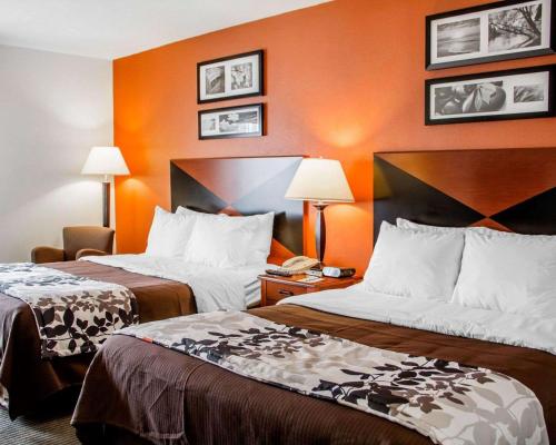 two beds in a hotel room with orange walls at Sleep Inn & Suites Oklahoma City Northwest in Oklahoma City