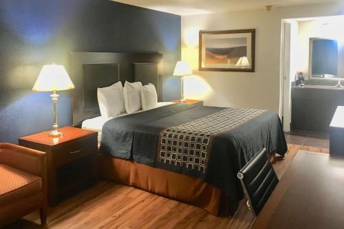 een hotelkamer met een bed en een stoel bij Rodeway Inn in Circleville
