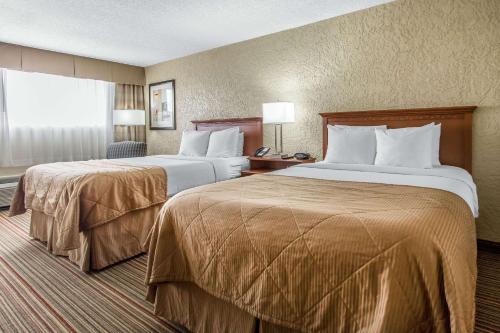 a hotel room with two beds and a window at Clarion Hotel Broken Arrow - Tulsa in Broken Arrow