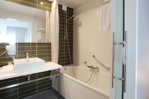 a bathroom with a sink and a bath tub and a mirror at Hotel De Pits in Heusden - Zolder