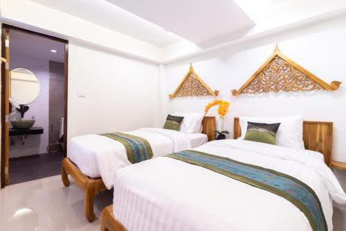 two beds in a room with white walls at Anumat Premium Budget Hotel in Chiang Mai