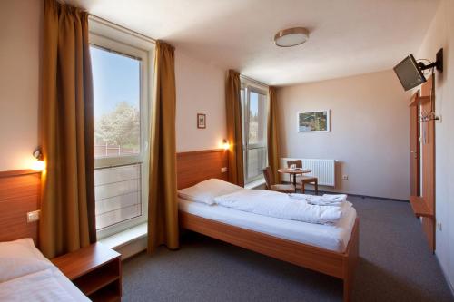 Penzion Ruland في برنو: غرفة نوم بسريرين ونافذة كبيرة
