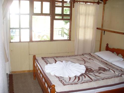 a bed in a room with two windows at Onder Pansiyon in Dalyan