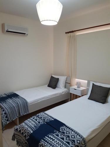 Duas camas num pequeno quarto com um candeeiro em Sirena Sunrise, Apartment 4 em Pafos