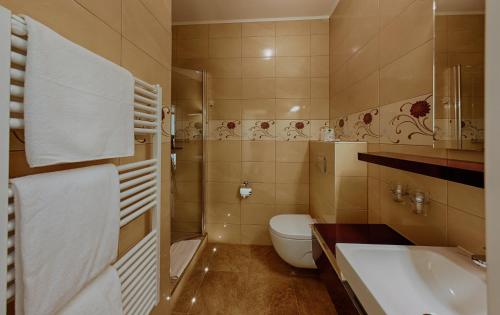 a bathroom with a toilet and a sink and a tub at Strandhotel Buckow gut-Hotels SEE in Buckow