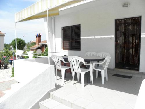 een patio met witte stoelen en een tafel op een huis bij Apartments Kuce - 150m from the beach with parking in Sušica