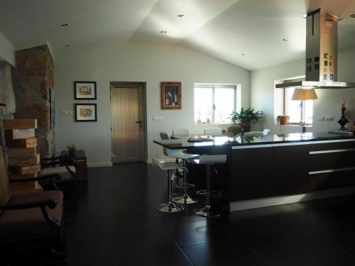 a kitchen with a counter and a bar with stools at Casa do Vale de Cerdeiras in Ancede