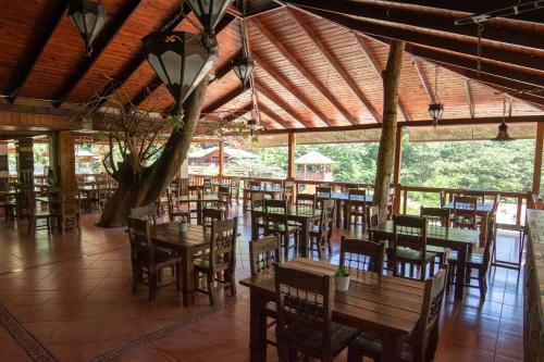 un restaurante con mesas y sillas de madera en un pabellón en Hotel Gran Jimenoa, en Jarabacoa