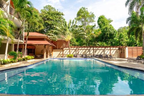 a swimming pool in front of a house with trees at Hotel Gran Jimenoa in Jarabacoa