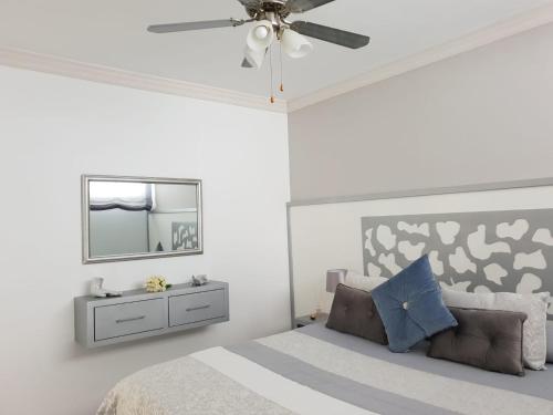 a white bedroom with a bed and a mirror at Luxury Tagara Beach in Puerto de Santiago