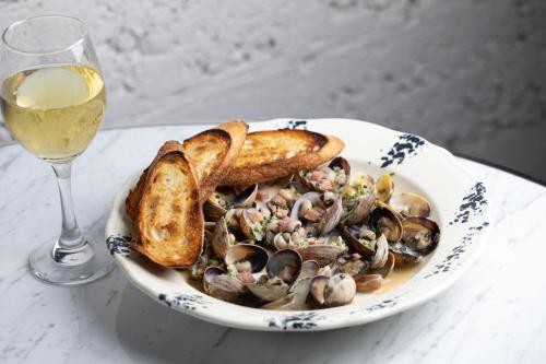 a plate of food with oysters and bread and a glass of wine at Palihotel Seattle in Seattle