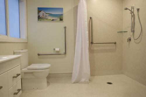 a white bathroom with a shower and a toilet at Villa93 in Katikati