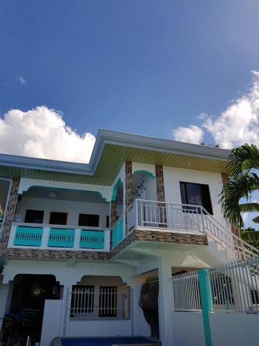 a house with a balcony and a palm tree at Rosita's Cottages by the Road in Moalboal