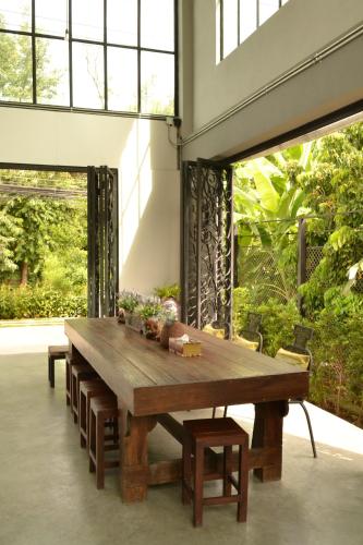 a large wooden table in a room with windows at Nornlamphun Boutique Hotel นอนลำพูน in Lamphun
