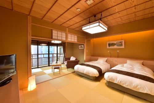 a bedroom with two beds and a tv and a balcony at Senjukaku in Yamanouchi