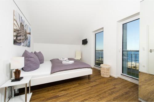 オルペニッツにあるKoje 23の白い壁のベッドルーム1室、紫色の枕付きのベッド1台が備わります。