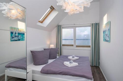 ein Schlafzimmer mit einem Bett mit violetter Bettwäsche und einem Fenster in der Unterkunft Kolibri in Olpenitz