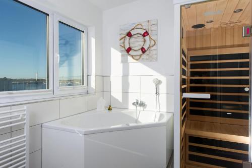 a white bathroom with a sink and a window at Koje 23 in Olpenitz
