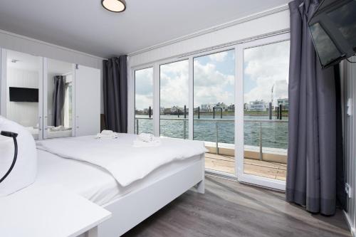 a white bedroom with a view of the water at Schwimmendes Haus Bente in Olpenitz