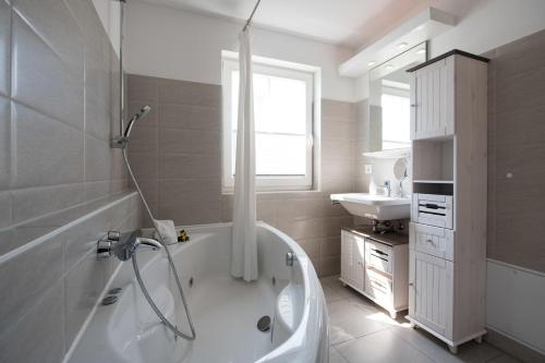 a white bathroom with a tub and a sink at Marina View in Olpenitz
