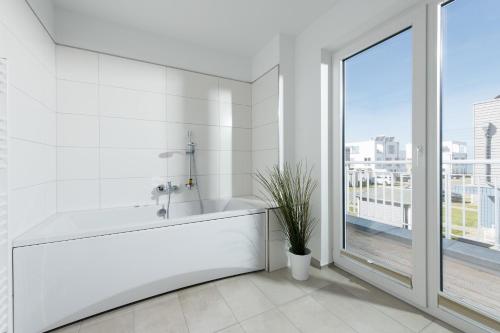 biała łazienka z wanną i oknem w obiekcie Küsten Lodge w mieście Olpenitz