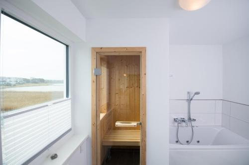 a bathroom with a bath tub and a window at Villa Kunterbunt in Olpenitz