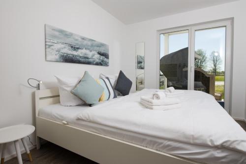 a bedroom with a large white bed with a window at Albatros in Olpenitz