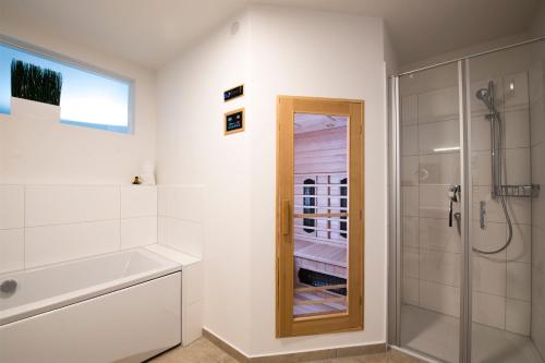 ein weißes Bad mit einer Dusche und einem Spiegel in der Unterkunft Fischermanns Freund in Olpenitz