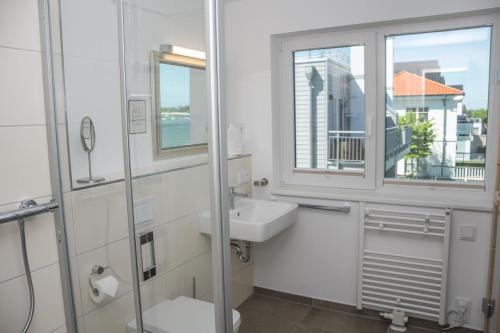 a white bathroom with a sink and a window at Achtern Schilf in Olpenitz