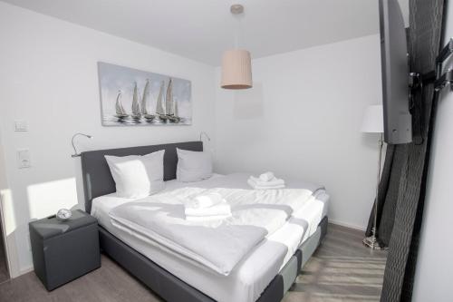 Schlafzimmer mit einem Bett mit weißer Bettwäsche und Kissen in der Unterkunft Silbermöwe in Olpenitz