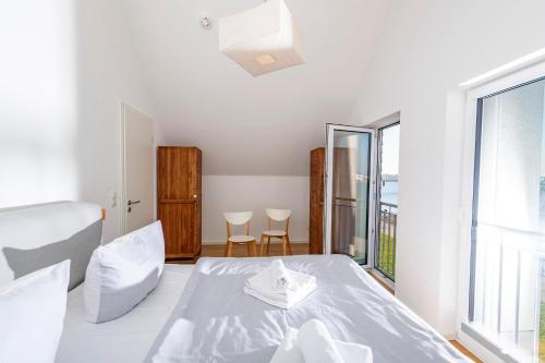 a white bedroom with a bed and a large window at Am Meer in Olpenitz