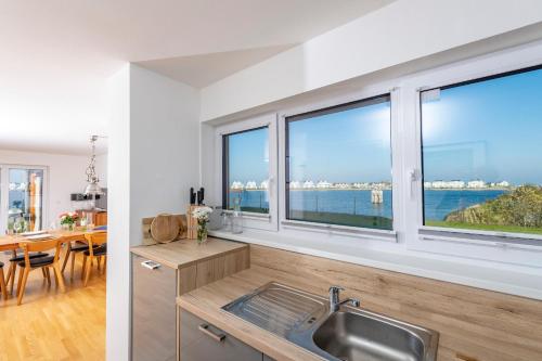 a kitchen with windows and a dining room with a view of the ocean at Am Meer in Olpenitz