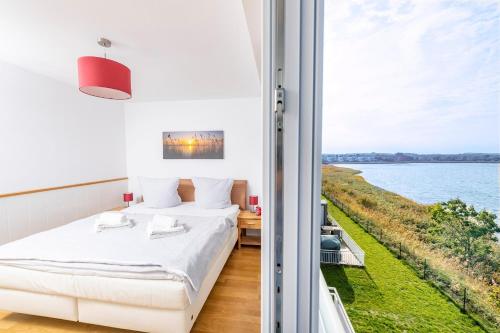 a bedroom with a bed and a view of the water at Schleikante in Olpenitz