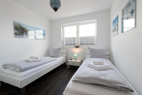 twee bedden in een kamer met witte muren bij Danish by Nature in Olpenitz