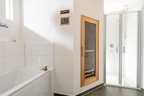 a white bathroom with a shower and a mirror at Schleikajüte in Olpenitz