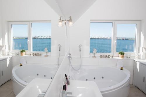 a white bathroom with two tubs and windows at Ostsee Koje in Olpenitz