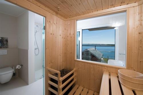 a wooden bathroom with a window and a toilet at Wind und Wasser in Olpenitz